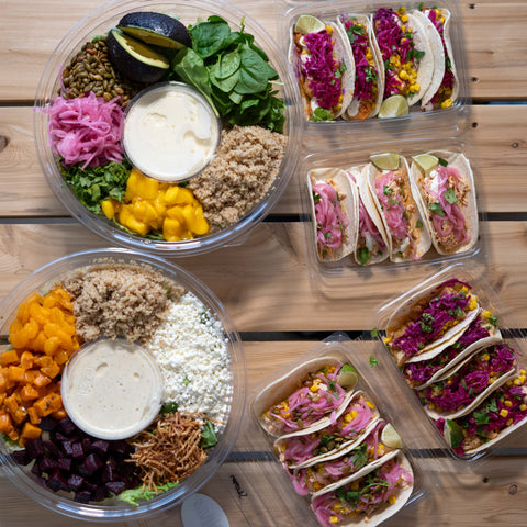 4 plateaux de tacos ainsi que 2 grandes salades traiteur placés sur une table de pic-nique, vue du haut