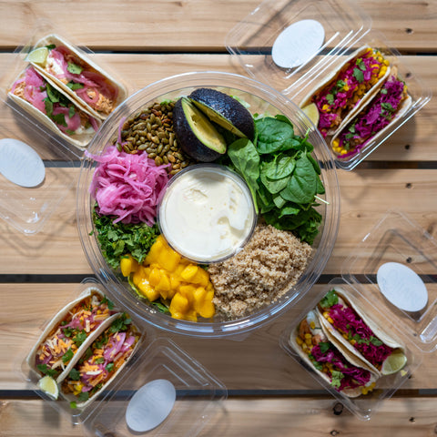 4 plateaux de tacos ainsi qu'une grande salade traiteur placés sur une table de pic-nique