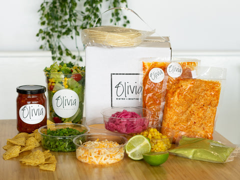 Boîte Olivia avec le contenu d'un kit à tacos mexicain placé autour: salade Chicco, chips et salsa, poulet et chorizo, condiments à tacos