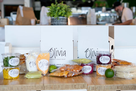 Boites Olivia avec contenants placés à l'avant comprenant sacs de protéines, limes, guacamole, tortillas, et condiments